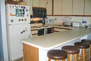 Eine Küche mit Kühlschrank, Mikrowelle, Herd und Barhocker.