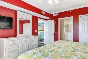 A bedroom with a bed, a dresser, a television, and a door leading to another room. - Aventurra 302 (Ocean City)