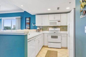 A kitchen with white cabinets, a microwave, an oven, and a sink. - Aventurra 302 (Ocean City)