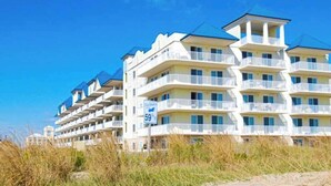 Ein mehrstöckiges Hotel mit Balkonen, Blick auf den Strand und einem Schild mit der Adresse.