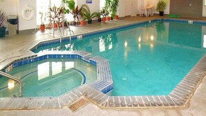Ein überdachter Pool mit Stufen zum Wasser, umgeben von Topfpflanzen und einem Rettungsring an der Wand.