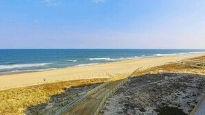 Ein Strand mit einem Zaun, dem Ozean und blauem Himmel.