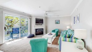 A living room with a fireplace, a sofa set, a coffee table, and a balcony with outdoor furniture. - Astoria 204 (Ocean City)
