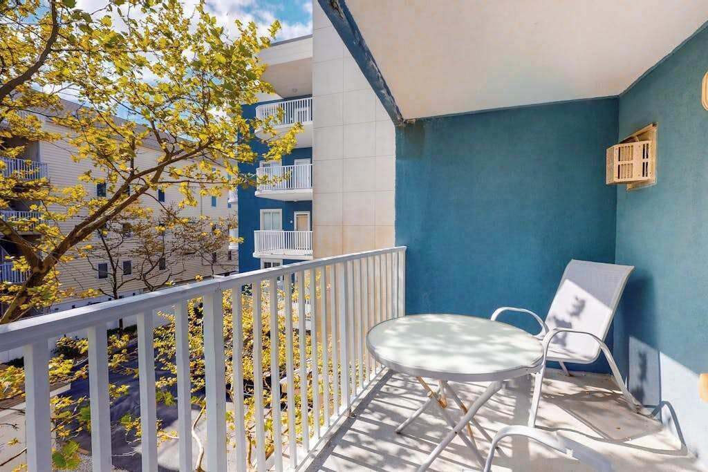 A balcony with a white railing, a small table, and two chairs.