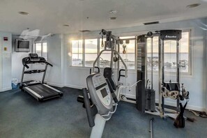 A gym with a treadmill, Nautilus equipment, and a view of the sea. - Comfy and Spacious Condo in Oceanside Complex w/Shared Pool, Balcony, WiFi (Ocean City)