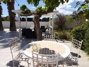 A round outdoor table with chairs, a pergola, and a white fence. - St Cyprien Zen and Bohemian, a swimming pool just for you (Saint-Cyprien)