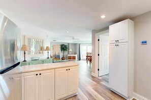 A modern kitchen with white cabinetry, a central island, and a dining area with a table and chairs. - 4100 #103 (Ocean City)