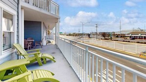 A balcony with green chairs and a table, overlooking a street with a bridge and buildings. - 4100 #103 (Ocean City)