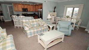 Ein Wohnzimmer mit einer Couch, Sesseln, einem Couchtisch und einem Essbereich mit Tisch und Stühlen.