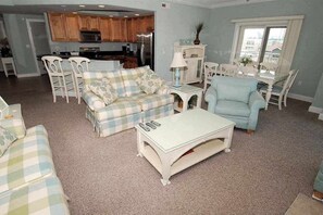 Ein Wohnzimmer mit einer Couch, Sesseln, einem Couchtisch und einem Essbereich mit Tisch und Stühlen.