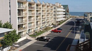 Ein mehrgeschossiges Hotel mit Balkonen, einem Parkplatz und Blick aufs Meer.