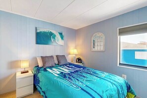 A bedroom with a bed, a nightstand, a lamp, a wall clock, and a window. - Top-floor condo with balcony, walk 1 minute to the beach (Ocean City)