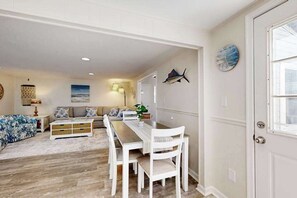 A living room with a dining table, white chairs, a sofa, and a decorative fish on the wall. - Belle Clair #1 (Ocean City)