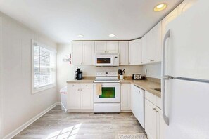 A kitchen with white cabinets, a microwave, an oven, and a refrigerator. - Belle Clair #1 (Ocean City)