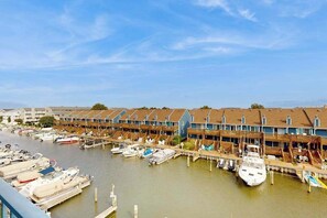 A marina with docked boats and a row of wooden buildings with balconies. - Blue Marlin 302 (Ocean City)