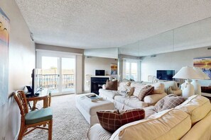 A modern living room with a sofa, armchairs, a coffee table, a TV, and a fireplace. - Blue Marlin 302 (Ocean City)
