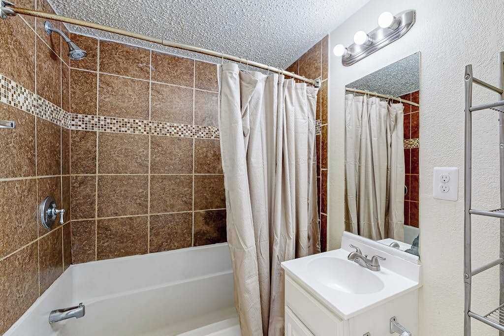 A bathroom with a bathtub, a shower, a sink, and a mirror.