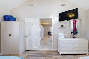 A room with a wardrobe, a television, and a door leading to another room. - Casa Serena (Ocean City)