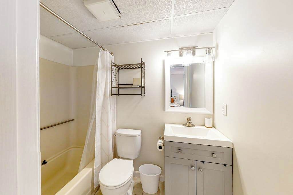 Un baño con ducha, inodoro, lavamanos y espejo.