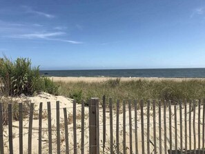 A beach with a wooden fence in the foreground and a clear sky. - Sea Mark 208 (Ocean City)