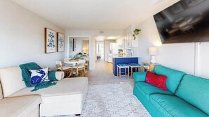 A living room with a sofa, a coffee table, and a TV mounted on the wall.