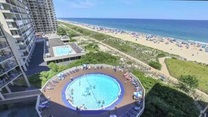 A rooftop pool with sun loungers, a view of the beach, and a high-rise building. - High Point South 6C (Ocean City)