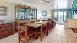 A dining area with a wooden table and chairs, a glass cabinet with dishes, and a view to the outside. - High Point South 6C (Ocean City)