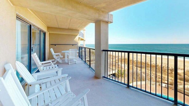 A balcony with white chairs, a table, and a view of the beach. - High Point South 6C (Ocean City)
