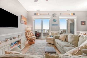 A living room with a TV, wicker chair, sofa, and a view of the outdoors. - Bayfront third-floor condo with sunset views, fast WiFi, and walkable location (Ocean City)