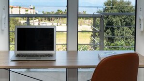 Un portatile su un tavolo con vista su un balcone e il mare.
