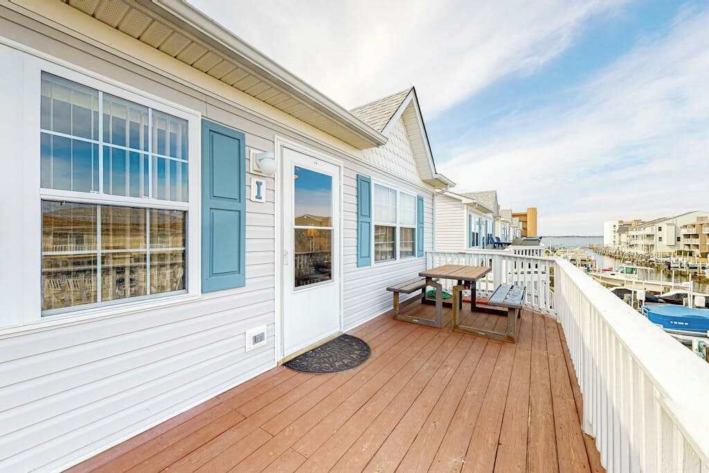 Eine Holzterrasse mit Tisch und Stühlen mit Blick auf einen Yachthafen und Boote.