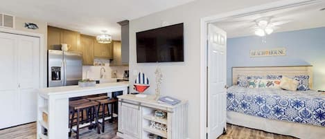 A compact living space with a kitchenette, a dining area, and a bedroom.
