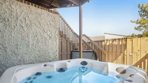 A hot tub in an outdoor setting with a wooden fence and a staircase leading up to a building. - Club Ocean Villa II 141 (Ocean City)