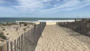 A sandy beach path leading to the ocean, bordered by wooden fences.