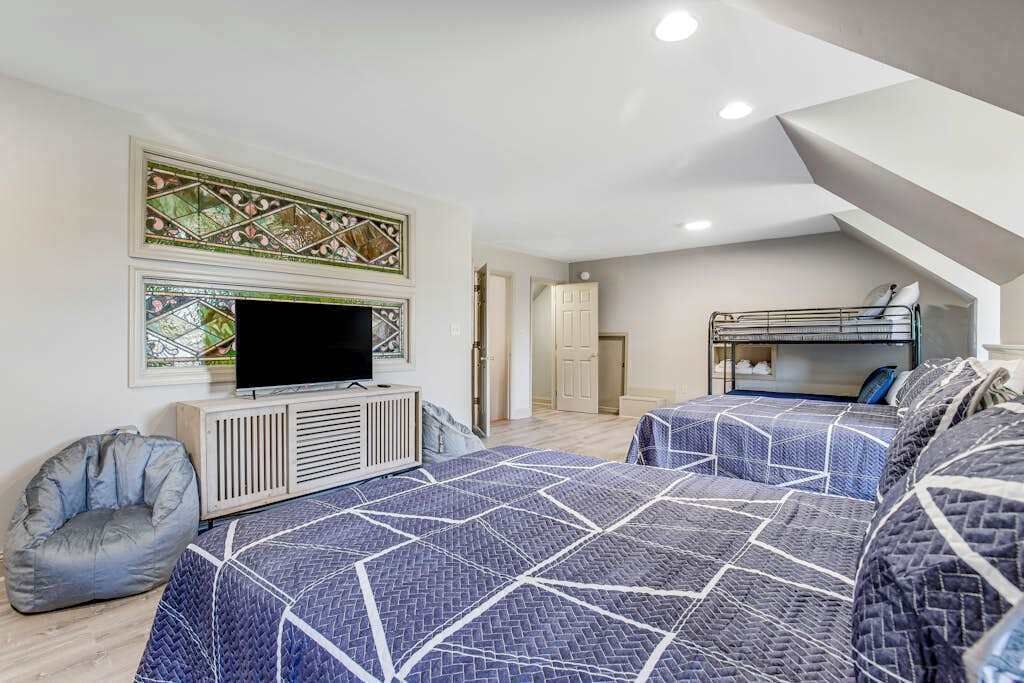 A bedroom with two beds, a television, a radiator, and a decorative wall piece.