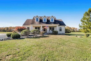 A two-story house with a front porch, a small American flag, and a well-maintained lawn. - Winery Getaway at Mariner’s Conclusion (Berlin)
