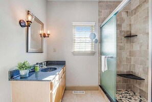 Une salle de bain avec un lavabo, un miroir et une douche.