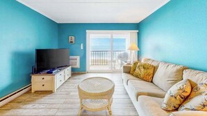 Uma sala de estar com televisão, sofá e poltrona de vime.