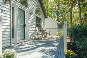 A house with a porch, sliding glass doors, and a small outdoor seating area. - Tranquil Woods (Ocean Pines)