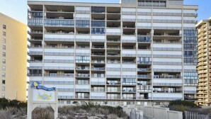 Monikerroksinen rakennus, jossa on parvekkeita, ja sen edessä on hiekkapintainen alue. Rakennuksen kyltissä lukee: ”High Point North”.