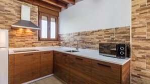 Una cocina con armarios de madera, encimera blanca, estufa integrada y salpicadero de piedra.