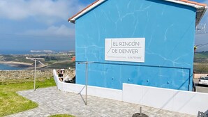 Un edificio azul con la leyenda 'EL RINCÓN DE DENVER' y una vista del paisaje al fondo.