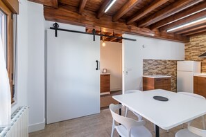 Una cuina moderna amb un relleu de pedra, armaris de fusta i un frigorífic blanc.
