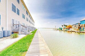 A waterfront hotel with a long dock, air conditioning units, and a grassy walkway. - Bayspot L-101 (Ocean City)