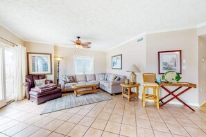 A living room with a sofa, armchairs, a coffee table, a floor lamp, and a ceiling fan. - Bay & ocean views at Sea Palms - free WiFi, private washer/dryer & dog-friendly (Ocean City)