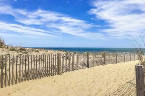 A sandy beach with a wooden fence and a clear blue sky. - Bay & ocean views at Sea Palms - free WiFi, private washer/dryer & dog-friendly (Ocean City)