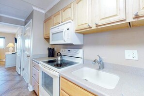 A modern kitchen with white appliances, wooden cabinets, and a large window. - Oceanfront Condo with Balcony, Gorgeous Views, Washer/Dryer & Free WiFi (Ocean City)