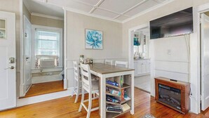 Una habitación con una mesa de comedor, sillas, una estantería, una chimenea y un televisor.