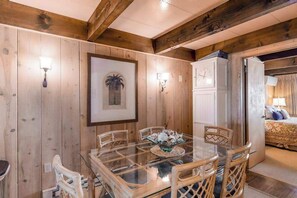 A wooden-paneled room with a glass-top dining table, wicker chairs, and a framed picture on the wall. - Oceanfront Townhome w/ Multiple Decks, Amazing Views, W/D & Beach Access (Ocean City)