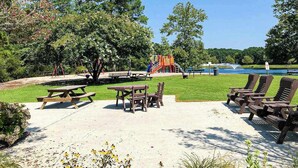 Ein Park mit Picknicktischen, Liegestühlen, einem Spielplatz und einem See.